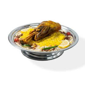 Abu Mubarak Lambshank Mandi for one person, featuring a large, tender slow-cooked lamb shank on a bed of yellow and white aromatic smoked basmati rice, garnished with lemon, cucumber, and a green chili on a silver platter.
